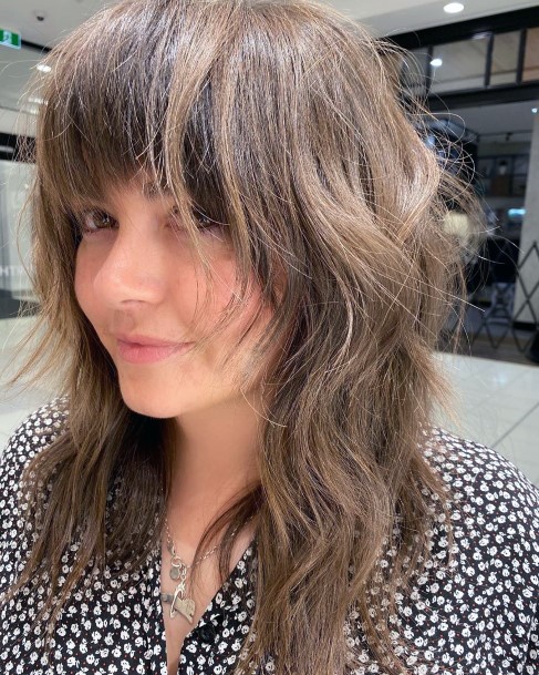 Female With Shag Hairstyle Medium Brown Color And Thick Bangs