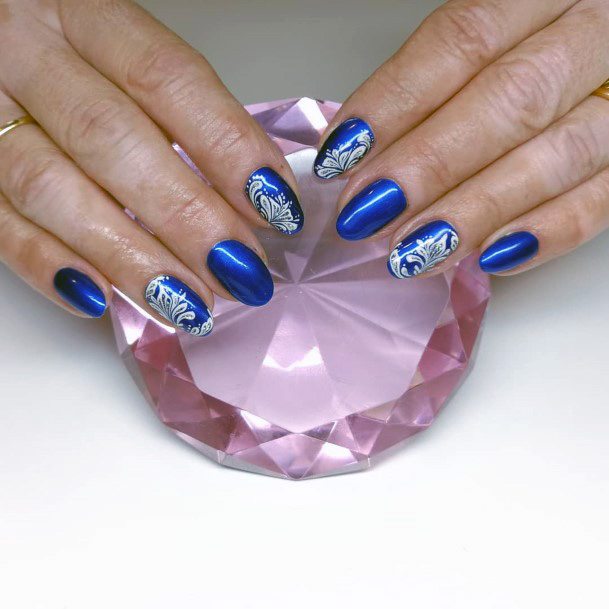 White Floral Art On Rich Blue Nails For Women