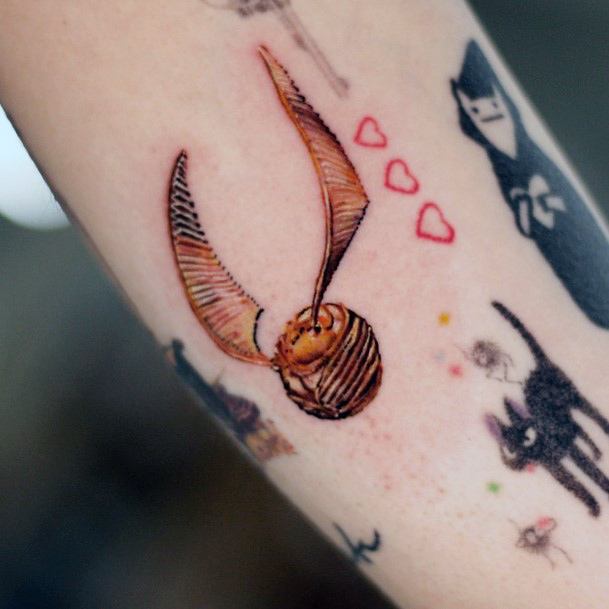 Woman With Fabulous Golden Snitch Tattoo Design