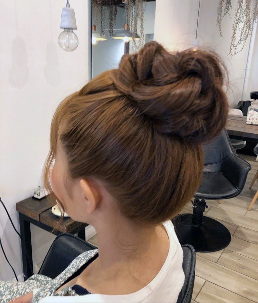 Woman With Pumpkin Colored Hair In A Top Knot Hairstyle